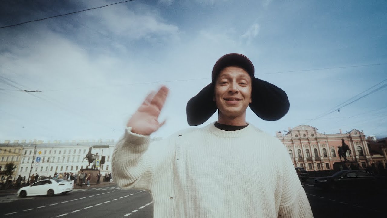 A man in a white sweater and a hat with ear flaps standing on a street in St. Petersburg, Russia.